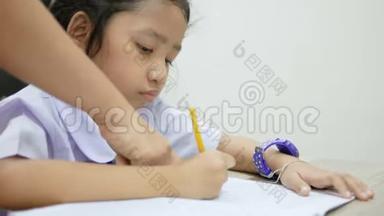 亚洲小女孩穿着泰<strong>国学</strong>生制服在木桌上做作业，选择焦点浅田深